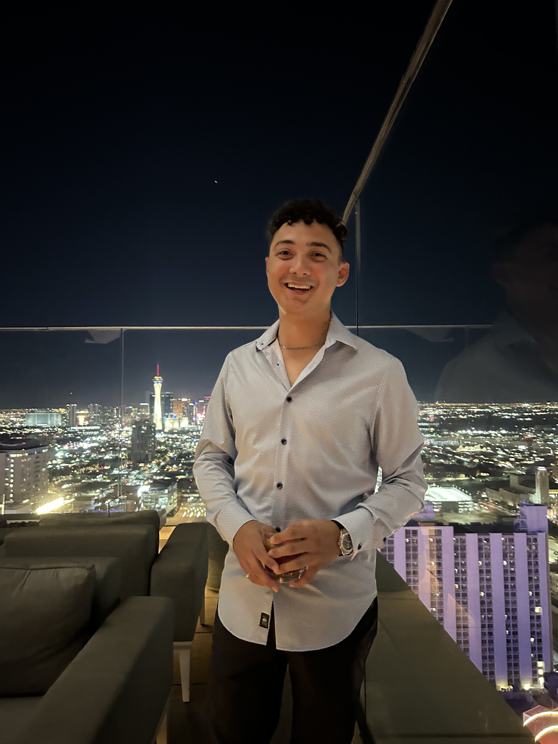 Thomas holding a drink on a Las Vegas rooftop at night